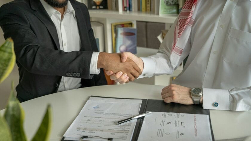 A handshake between a business owner and a digital marketing strategist, with digital analytics in the background.