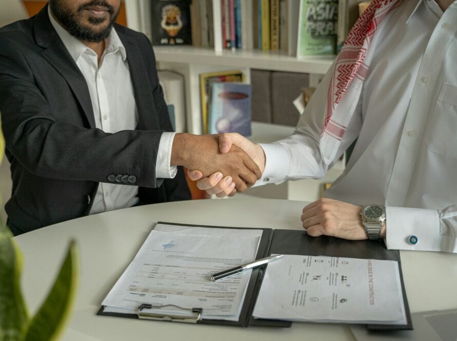 A handshake between a business owner and a digital marketing strategist, with digital analytics in the background.